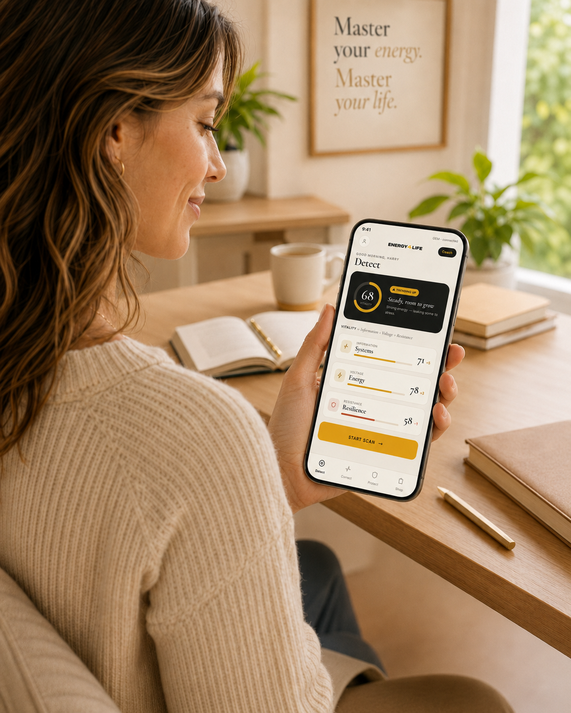 A woman at her desk checking her Vitality Score on the GEM app, showing a score of 68 and the Systems, Energy and Resilience breakdown