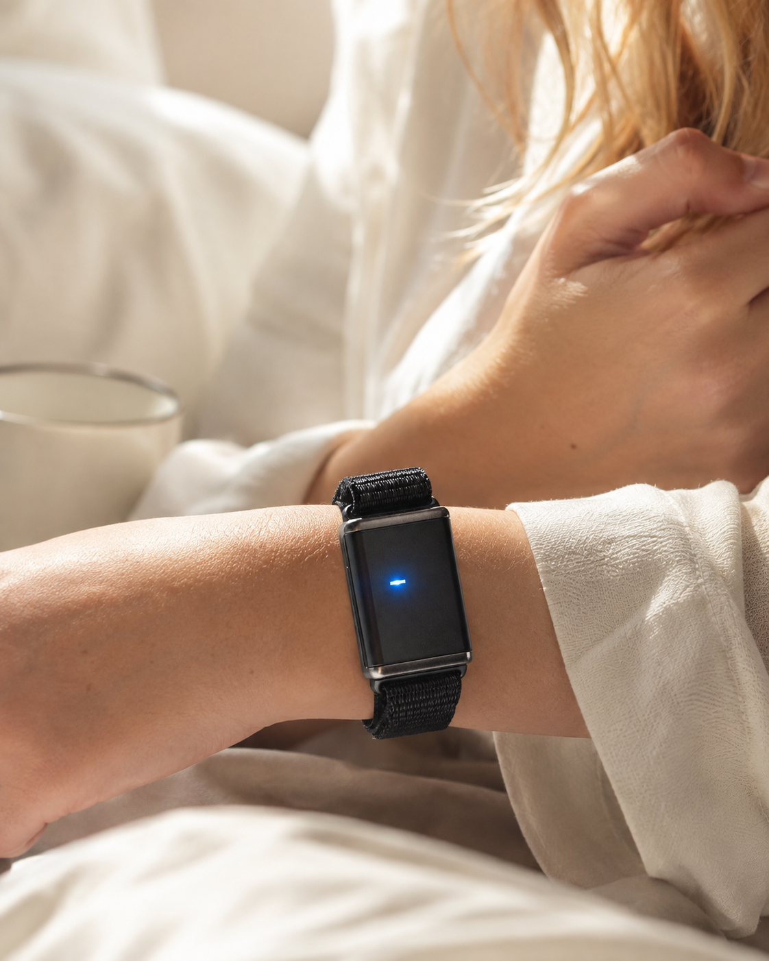 A close-up of the GEM on someone's wrist while relaxing in bed